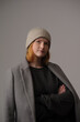 © Юрий Горид - young girl model in beige hipster hat and coat isolated on light background. Product photo mockup for fashion brands and marketplaces, woolen cap, turkish textiles.