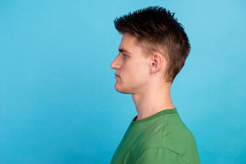 Side view of serious handsome man in casual shirt stand look left, empty copy space studio shot isolated on blue background