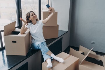 Wall Mural - Girl blogger greeting followers in social network, doing overview of new apartment on moving day