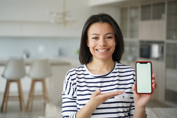 new mobile apps. smiling female showing phone with mockup empty screen at home. online store offer