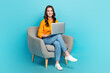 Full length portrait of positive nice person sit chair use wireless netbook isolated on blue color background