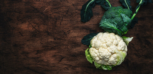 Autumn food background with cauliflower and broccoli on old rustic wood kitchen table, top view, copy space banner