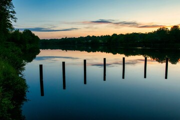 Wall Mural - Mesmerizing scene of orange sunset sky over reflecting lake water with trees