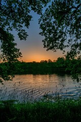 Sticker - Beautiful view of tree leaves and plants by the dunes of lake under sunset sky, vertical shot