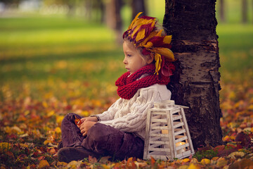 Sticker - Sad toddler child, blond boy with a leaf crown, sitting next to a tree with lantern with candle