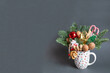 Christmas edible composition with nuts, sweets, nobilis and christmas decor in a mug on a gray background