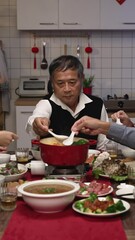 Wall Mural - Vertical Screen: asian extended family blowing and tasting the hot delicious soup with spoons while they are gathering together for new year's reunion meal at home in the evening