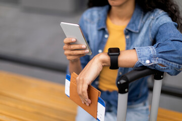 Cropped of woman tourist holding flight tickets and smartphone, closeup