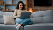 © Yuliia - Relaxed freelancer woman SMM specialist web programmer housewife student businesswoman girl woman sitting on couch at home typing laptop working remote distant job quarantine using wireless computer