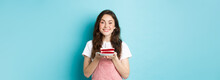 Celebration And Holiday. Smiling Young Woman Celebrating Birthday, Holding Cake With Candle And Looking Dreamy At Camera, Standing Over Blue Background