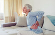 © Jelena Stanojkovic - Tired upset elderly woman feeling strong lower back pain after sleeping in incorrect posture on uncomfortable mattress. Senior 60s lady with closed eyes sitting on bed, holding painful lumber muscles.