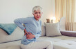 © Jelena Stanojkovic - Cropped shot of a mature woman holding her lower back in discomfort due to pain in that area.