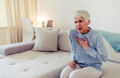 © Jelena Stanojkovic - Senior adult elderly women sit on bed with chest pain suffering from heart attack in the bedroom.Healthcare and medical concept.