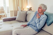 © Jelena Stanojkovic - Shot of a senior woman suffering from chest pain while sitting on the sofa at home. Cropped closeup of an mature woman experiencing cardiac discomfort at home.