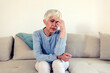 © Jelena Stanojkovic - Photo of Woman suffering from stress or a headache grimacing in pain as she holds forehead with her hand, with copy space. Caucasian middle age woman looking sad.