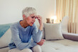 © Jelena Stanojkovic - Photo of Woman suffering from stress or a headache grimacing in pain as she holds forehead with her hand, with copy space. Caucasian middle age woman looking sad.
