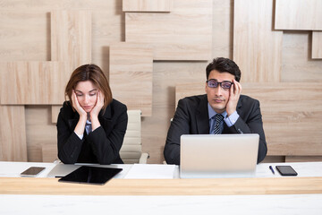 Stressed male and female business persons sitting at desk, hard thinking about problem. Businessman showing businesswoman bad news, company bankruptcy, economic crisis and mistake in work