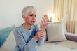 © Jelena Stanojkovic - Frustrated stressed middle aged female retiree having painful feelings in bones, arthritis osteoporosis concept. Shot of an woman sitting alone on sofa at home and suffering from arthritis in her hand