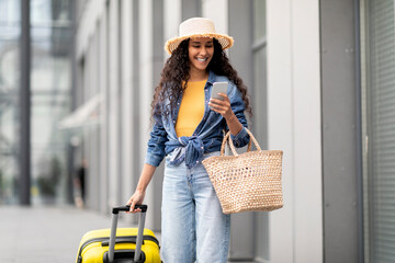 Wall Mural - Pretty young woman going vacation, walking by airport, using smartphone