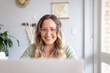 © Austockphoto - Smiling woman with green blouse wearing an eyeglass while looking at a laptop screen