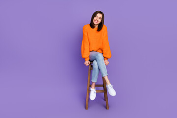 Poster - Full body photo of pretty young girl sit wooden bar chair toothy smile wear trendy orange knitwear look isolated on violet color background