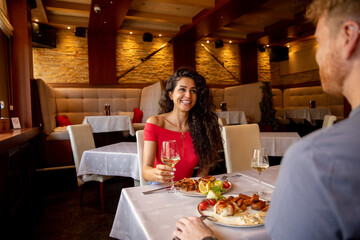 Wall Mural - Young couple having lunch with white wine in the restaurant