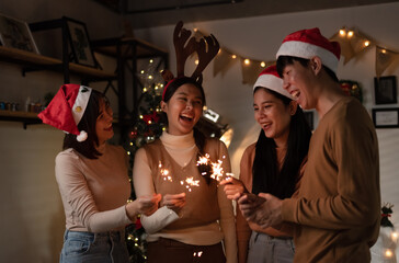 Group of asian friends celebrating christmas party or new year with bengal lights. Friends having fun together at home party.