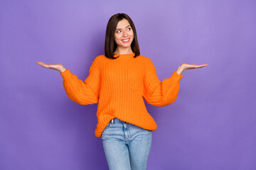 Wall Mural - Photo portrait of lovely young woman hands scales look empty space wear trendy knitwear orange outfit isolated on violet color background