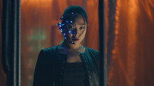 Cyberpunk Girl In A Black Leather Jacket Trapped Behind Black Hanging Rods. Intense Facial Expressions. Asian Girl With Futuristic Glasses And Headset. Cyborg, Sci-fi, Neon Lights.