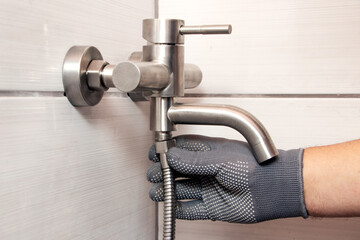 Wall Mural - A plumber connects a hose to a faucet in a bathroom