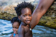 © LEONARDO BORGES ADF - Imagen de un pequeño niño afroamericano con cabello afro en la playa mirando a cámara mientras juega con su pequeña hermana en un día de verano.