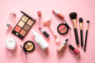 Wall Mural - Makeup cosmetic products on pink background. Cream, lipstick, shadow and brushes. Flat lay image with copy space.