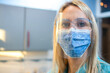 Close up of young female nurse wearing protective face shield and mask in office.