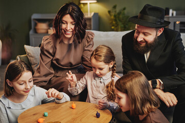 Wall Mural - High angle view at modern jewish family playing traditional dreidel game in cozy home setting