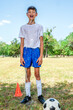 Male youth soccer player standing on the field soaking wet