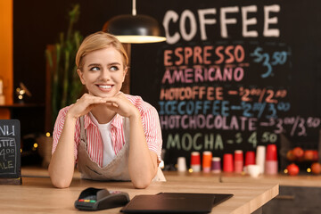 Wall Mural - Young female barista at table in cafe