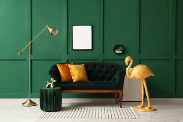 Interior of room with golden flamingo, sofa and blank photo frame near green wall