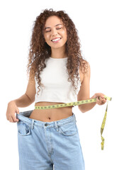 Wall Mural - Happy young African-American woman in loose clothes and with measuring tape on white background. Diet concept