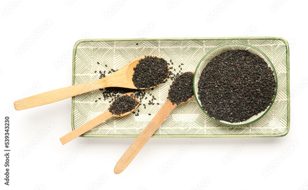 Plate with spoons of black sesame seeds on white background