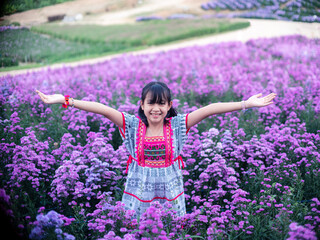 Wall Mural - A brightly smiling girl in native dress stands in a field of margarets flowers