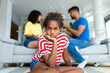 Family Conflicts. Sad little black girl looking away while her parents arguing in the background, upset child doesn't want to hear quarrel, stressed kid sitting alone, selective focus