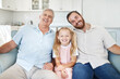 © Allistair F/peopleimages.com - Portrait in home, girl with dad and grandfather on living room sofa in Australia. Happy family with senior grandparent, smile together in lounge and elderly generation man relax on couch with child