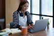 © Jirapong - Portrait of a young, attractive Asian teenage girl using a computer and drinking coffee while studying online in the morning at the library