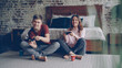 © silverkblack - Cute young couple boyfriend and girlfriend are playing videogame holding joysticks sitting on bedroom floor at home. Emotional lovers are enjoying computer game.