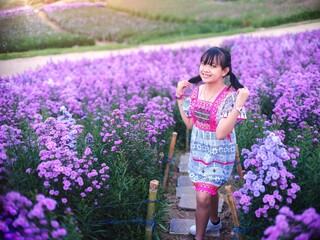 Wall Mural - A brightly smiling girl in native dress stands in a field of margarets flowers