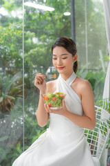 Wall Mural - Close-up of pretty girl eating fresh vegetable salad