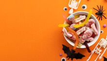 A Bowl Full Of Halloween Candy Sweets On An Orange Background. Trick Or Treat Background