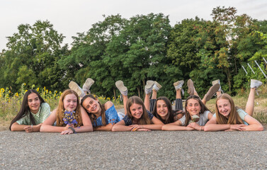 Seven teenage girls lying on a street, copy space