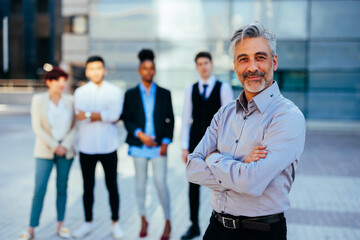 Senior businessman standing in front of team