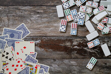 Scattered Playing Cards And Dominoes On A Rustic Wooden Surface